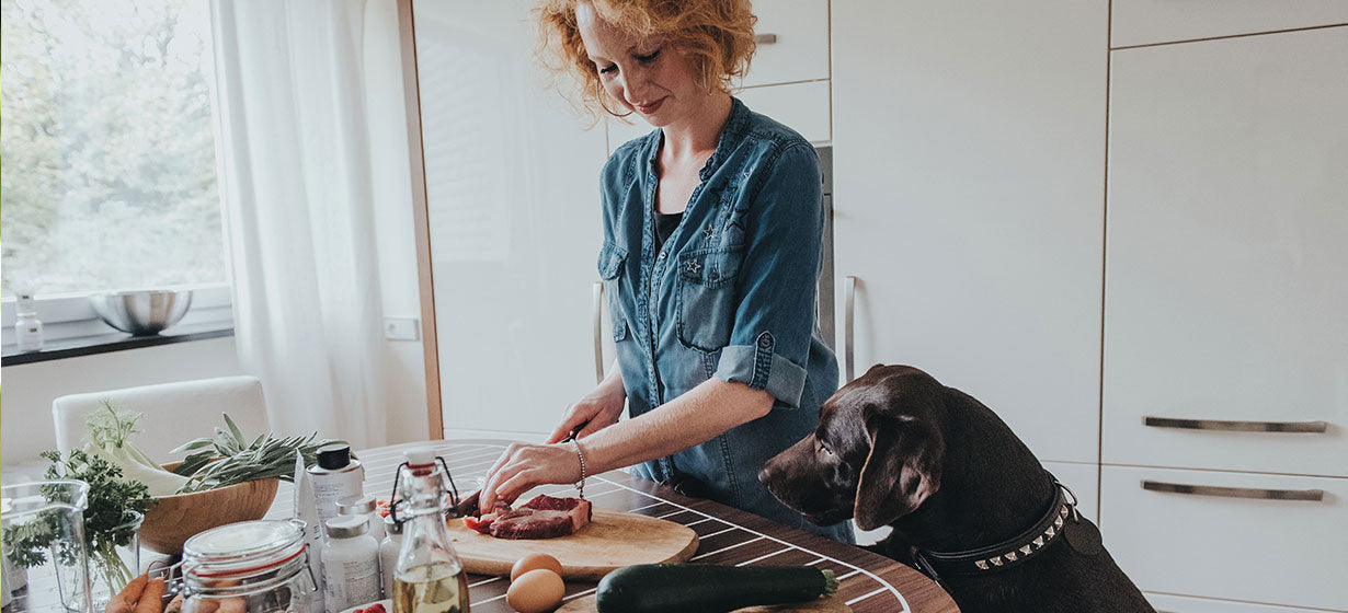 woman cooking steak with dog